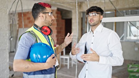 Téléchargez les photos : Deux hommes bâtisseur et architecte debout ensemble parlant sur le chantier de construction - en image libre de droit
