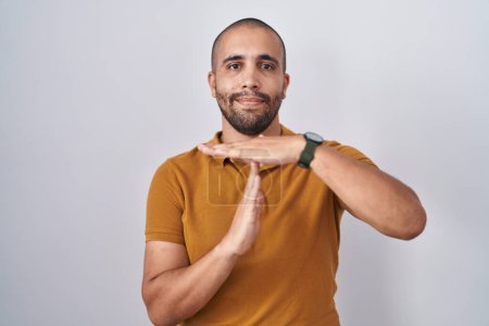 Téléchargez les photos : Homme hispanique avec la barbe debout sur fond blanc faisant le temps geste avec les mains, visage frustré et sérieux - en image libre de droit