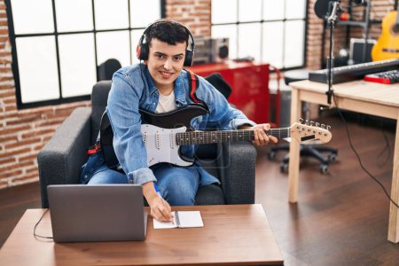 Photo for Young non binary man musician composing song playing electrical guitar at music studio - Royalty Free Image
