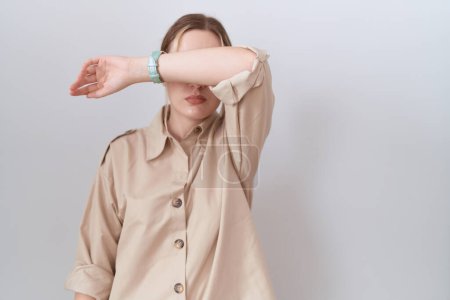 Foto de Mujer caucásica joven con camisa casual que cubre los ojos con el brazo, con un aspecto serio y triste. concepto de ocultamiento y rechazo sin visión - Imagen libre de derechos