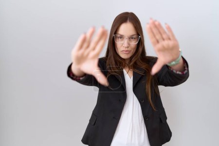 Téléchargez les photos : Belle femme brune portant une veste d'affaires et des lunettes faisant cadre en utilisant les paumes des mains et des doigts, perspective de la caméra - en image libre de droit