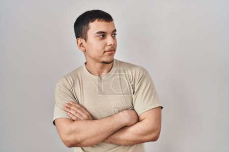 Téléchargez les photos : Jeune homme arabe portant t-shirt décontracté regardant sur le côté avec les bras croisés convaincu et confiant - en image libre de droit