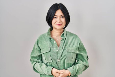 Téléchargez les photos : Jeune femme asiatique debout sur fond blanc avec les mains jointes et les doigts croisés souriant détendu et joyeux. succès et optimisme - en image libre de droit