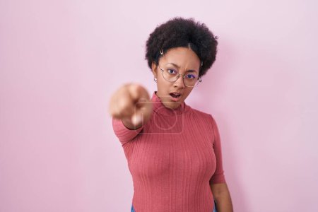 Photo for Beautiful african woman with curly hair standing over pink background pointing displeased and frustrated to the camera, angry and furious with you - Royalty Free Image
