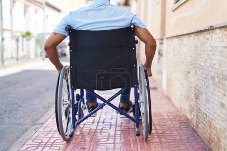 Photo for Young latin man sitting on wheelchair at street - Royalty Free Image