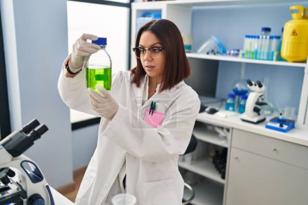 Téléchargez les photos : Young beautiful hispanic woman scientist measuring liquid at laboratory - en image libre de droit