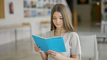 Photo for Young beautiful girl student reading book at library - Royalty Free Image