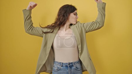 Téléchargez les photos : Jeune belle femme hispanique souriant confiant faire un geste fort avec les bras sur fond jaune isolé - en image libre de droit