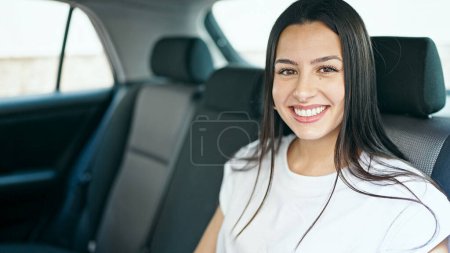 Téléchargez les photos : Jeune belle hispanique femme passager assis sur la voiture souriant à la rue - en image libre de droit