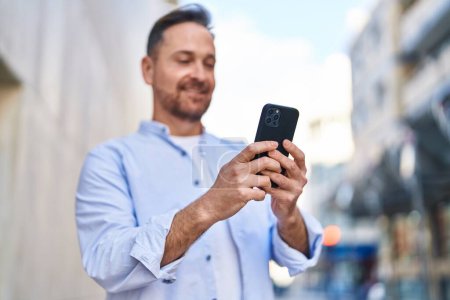 Téléchargez les photos : Young caucasian man smiling confident using smartphone at street - en image libre de droit