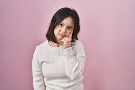 Photo for Woman with down syndrome standing over pink background with hand on chin thinking about question, pensive expression. smiling and thoughtful face. doubt concept. - Royalty Free Image
