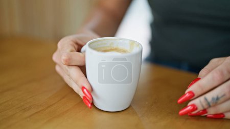 Foto de Mujer rubia joven sosteniendo taza de café sentado en la mesa en la cafetería - Imagen libre de derechos