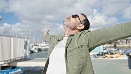 Téléchargez les photos : Homme d'âge moyen respirant les bras ouverts au port - en image libre de droit