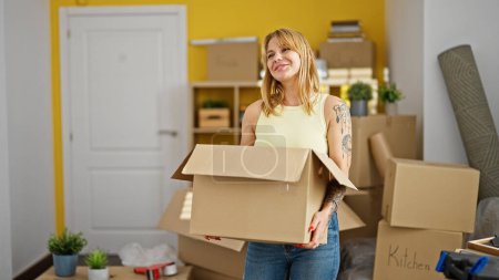 Photo for Young blonde woman smiling confident holding package at new home - Royalty Free Image