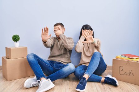 Photo for Young couple moving to a new home covering eyes with hands and doing stop gesture with sad and fear expression. embarrassed and negative concept. - Royalty Free Image