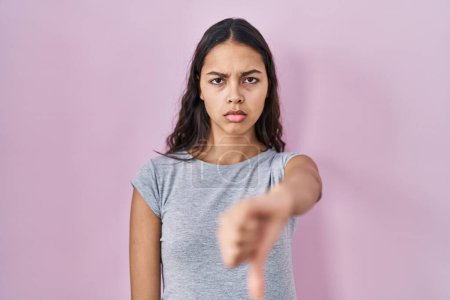 Photo for Young brazilian woman wearing casual t shirt over pink background looking unhappy and angry showing rejection and negative with thumbs down gesture. bad expression. - Royalty Free Image