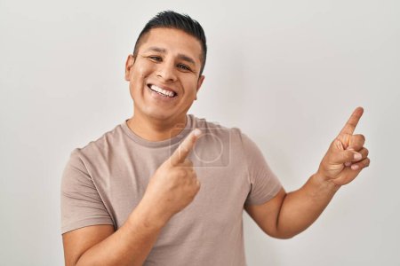 Photo for Hispanic young man standing over white background smiling and looking at the camera pointing with two hands and fingers to the side. - Royalty Free Image
