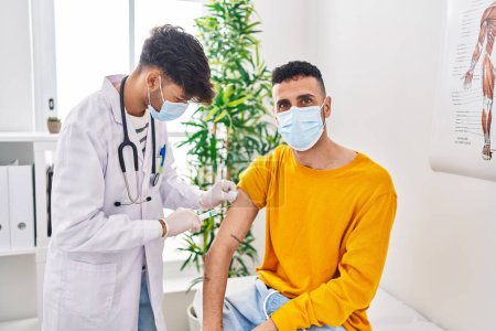 Téléchargez les photos : Two man doctor and patient vaccinating at clinic - en image libre de droit