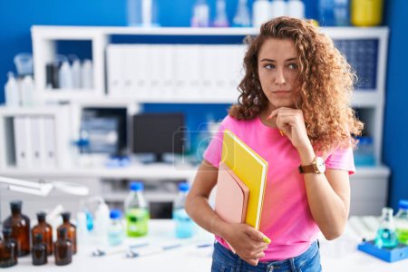 Photo for Young caucasian student woman at scientist laboratory serious face thinking about question with hand on chin, thoughtful about confusing idea - Royalty Free Image