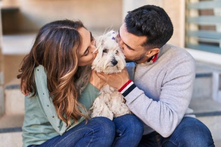 Téléchargez les photos : Homme et femme embrassant chien debout ensemble dans la rue - en image libre de droit