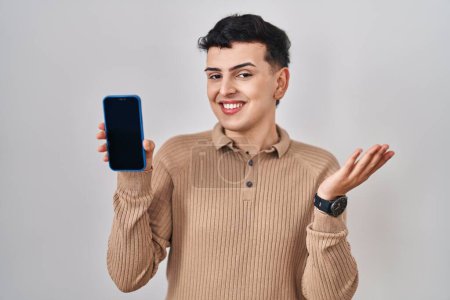 Photo for Non binary person holding smartphone showing blank screen celebrating achievement with happy smile and winner expression with raised hand - Royalty Free Image