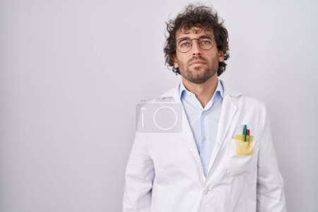 Photo for Hispanic young man wearing doctor uniform relaxed with serious expression on face. simple and natural looking at the camera. - Royalty Free Image