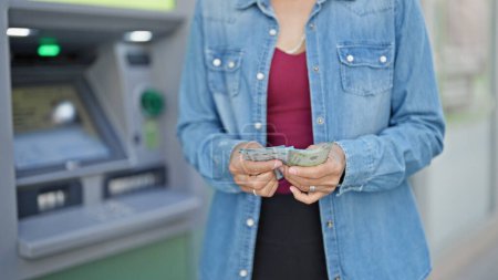 Foto de Joven hermosa mujer hispana contando billetes chilenos en cajero bancario - Imagen libre de derechos