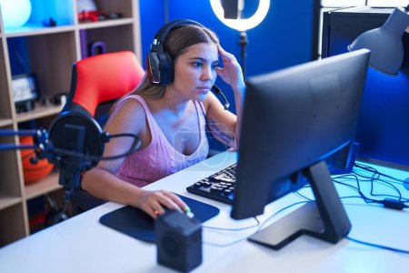 Photo for Young beautiful hispanic woman streamer playing video game using computer at gaming room - Royalty Free Image
