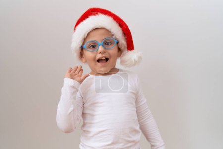 Photo for Little hispanic boy wearing glasses and christmas hat celebrating achievement with happy smile and winner expression with raised hand - Royalty Free Image
