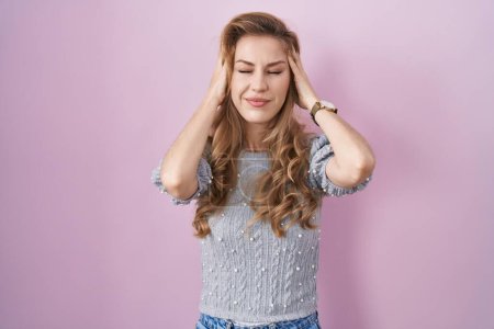 Photo for Beautiful blonde woman standing over pink background with hand on head, headache because stress. suffering migraine. - Royalty Free Image
