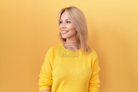 Photo for Young caucasian woman wearing yellow sweater looking away to side with smile on face, natural expression. laughing confident. - Royalty Free Image