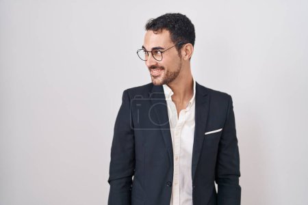 Foto de Hombre hispano de negocios guapo de pie sobre fondo blanco sonriendo mirando hacia un lado y mirando hacia otro pensando. - Imagen libre de derechos