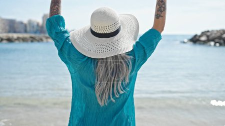 Foto de Turista mujer de pelo gris de mediana edad de pie hacia atrás en la playa - Imagen libre de derechos