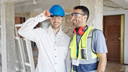 Téléchargez les photos : Deux hommes constructeur et architecte souriant confiant debout ensemble sur le chantier de construction - en image libre de droit