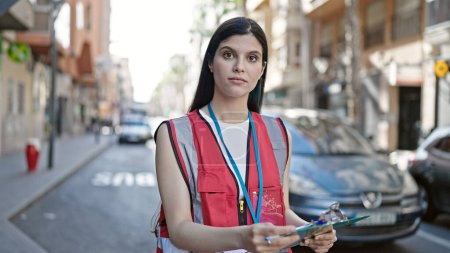 Photo for Young beautiful hispanic woman courier writing on clipboard at street - Royalty Free Image