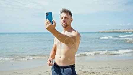 Téléchargez les photos : Jeune homme touriste faire selfie par smartphone à la plage - en image libre de droit