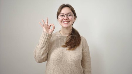 Foto de Joven mujer rubia sonriendo confiada haciendo buen gesto sobre fondo blanco aislado - Imagen libre de derechos
