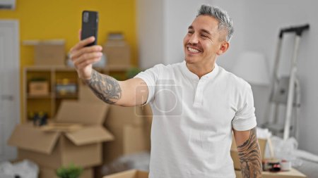 Photo for Young hispanic man make selfie by smartphone smiling at new home - Royalty Free Image