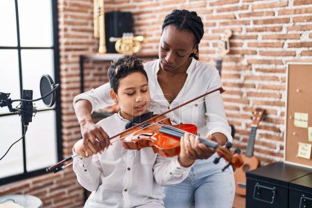 Foto de African american mother and son student learning play violin at music studio - Imagen libre de derechos