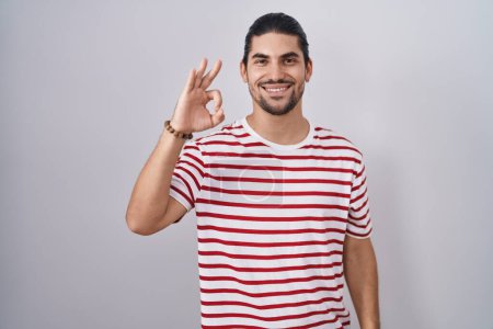 Photo for Hispanic man with long hair standing over isolated background smiling positive doing ok sign with hand and fingers. successful expression. - Royalty Free Image