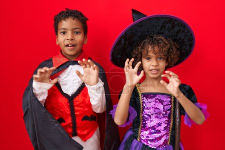 Photo for Adorable african american boy and girl wearing halloween costume doing fear gesture over isolated red background - Royalty Free Image
