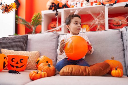 Photo for Adorable hispanic boy having halloween party holding balloon at home - Royalty Free Image