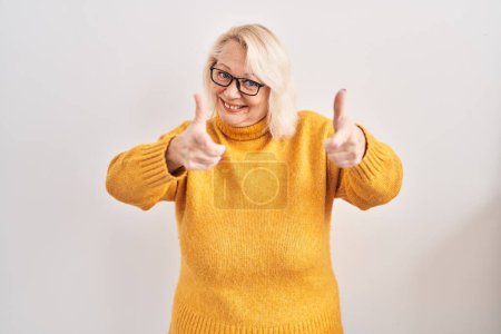 Photo for Middle age caucasian woman wearing glasses standing over background pointing fingers to camera with happy and funny face. good energy and vibes. - Royalty Free Image