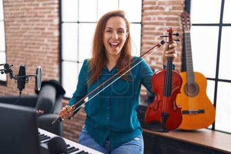Foto de Mujer morena tocando el violín sonriendo y riendo en voz alta porque divertido chiste loco. - Imagen libre de derechos