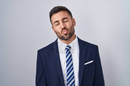 Photo for Handsome hispanic man wearing suit and tie looking at the camera blowing a kiss on air being lovely and sexy. love expression. - Royalty Free Image