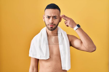 Photo for Young hispanic man standing shirtless with towel shooting and killing oneself pointing hand and fingers to head like gun, suicide gesture. - Royalty Free Image