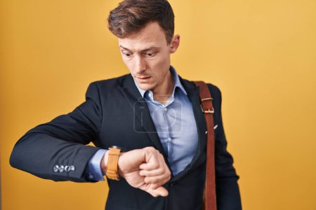Téléchargez les photos : Homme d'affaires caucasien sur fond jaune regardant le temps de la montre inquiet, peur de se faire tard - en image libre de droit
