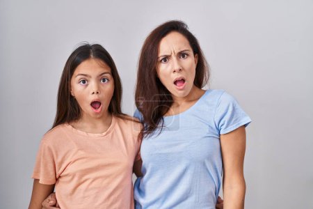 Téléchargez les photos : Jeune mère et sa fille debout sur fond blanc dans le visage de choc, l'air sceptique et sarcastique, surpris avec la bouche ouverte - en image libre de droit