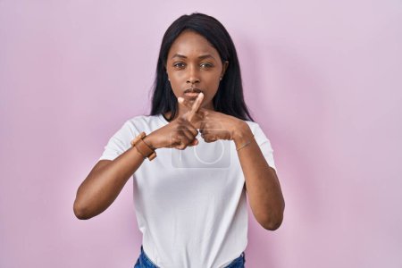 Foto de Mujer joven africana vistiendo casual camiseta blanca expresión rechazo cruzando dedos haciendo signo negativo - Imagen libre de derechos