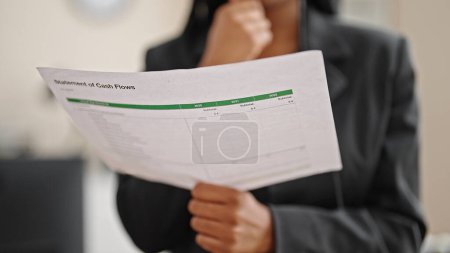 Téléchargez les photos : Femme afro-américaine ouvrière lisant un document au bureau - en image libre de droit